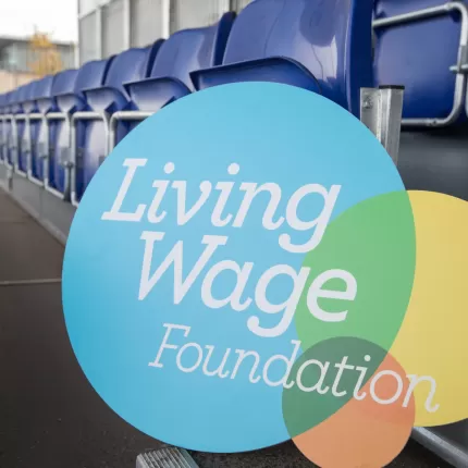A Living Wage Foundation foamboard propped up against seats on the Everton FC terraces