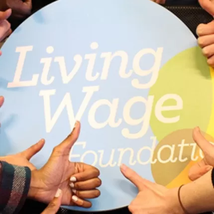 Hands in the shape of thumbs up gathered around Living Wage Foundation logo