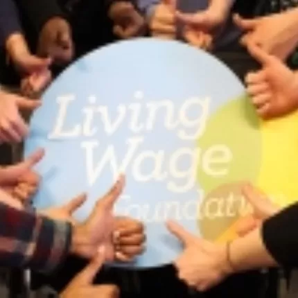 Hands in the shape of thumbs up gathered around Living Wage Foundation logo