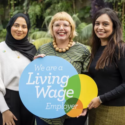 Three women holding Living Wage logo