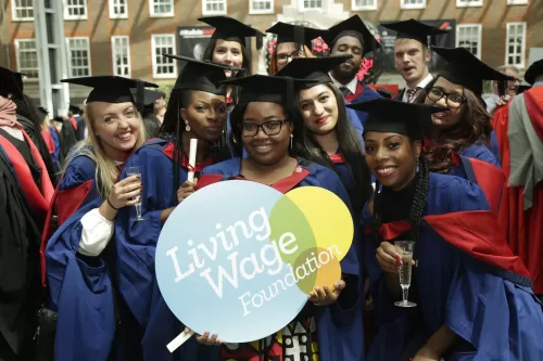 University Student graduates hold Living Wage sign