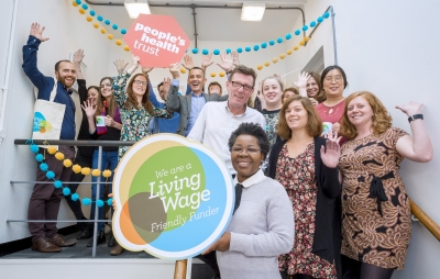 Team of People's Health Trust holding up a Living Wage Employer logo
