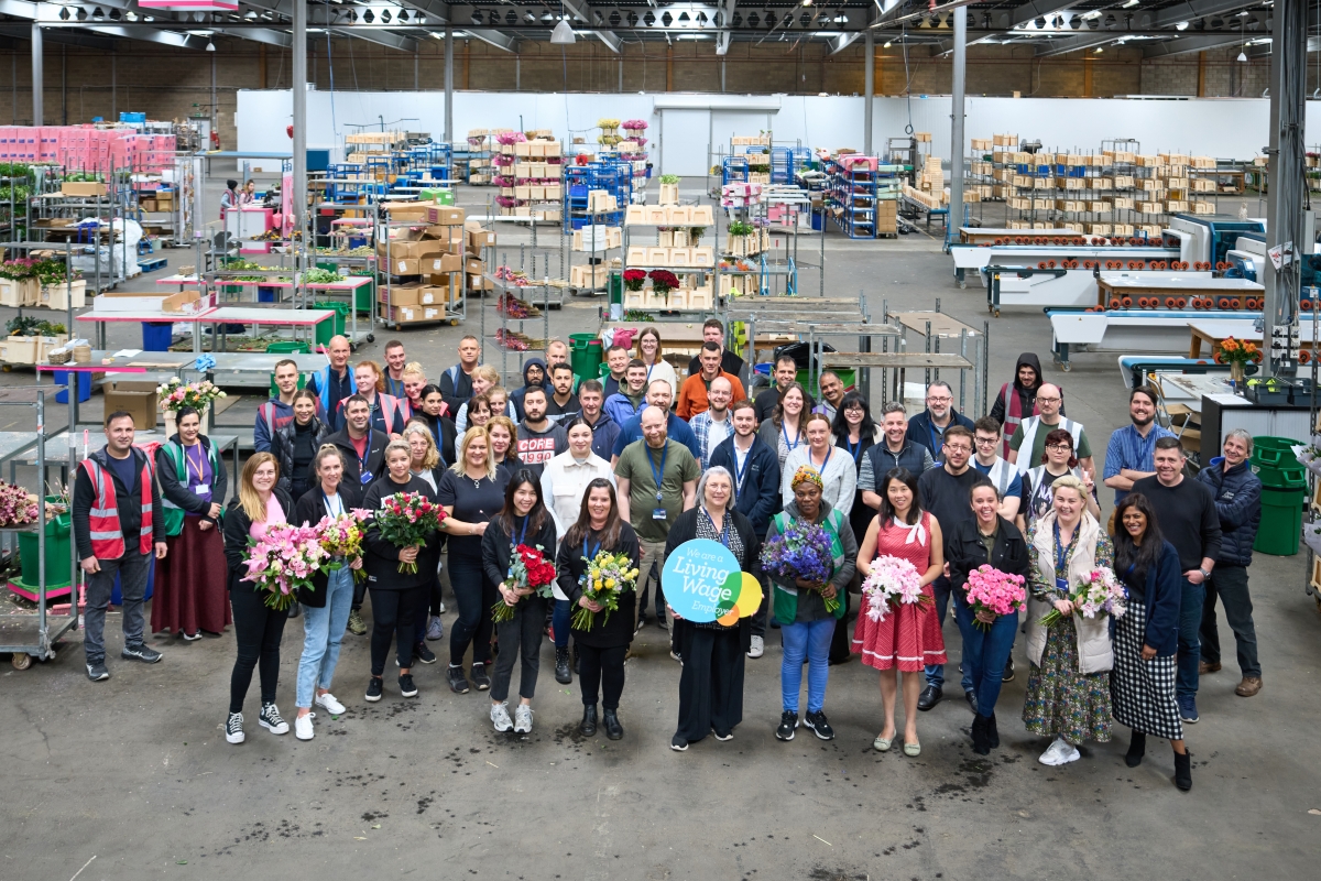 Arena flowers staff in their warehouse with the Living Wage logo on display