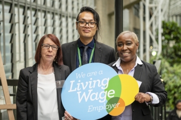 three people holding Living Wage sign