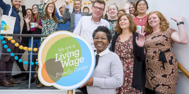 Group of people celebrating with the Living Wage funder logo